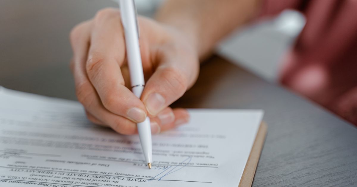 Una persona firma un documento sobre un escritorio